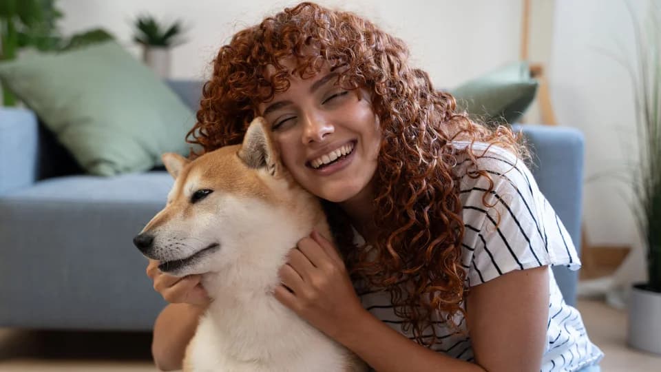 Happy owner cuddling her Shiba Inu in her living room
